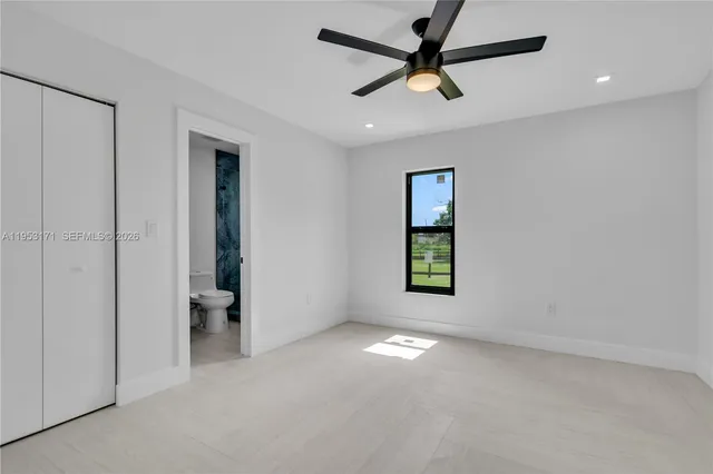 an empty room with closet and a ceiling fan