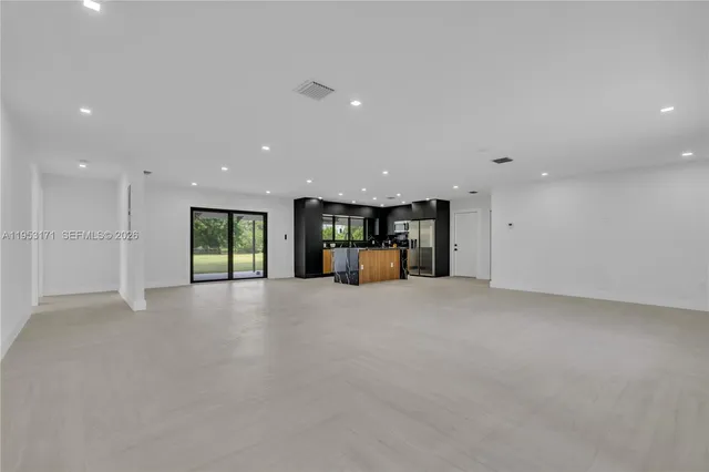 a view of empty room with kitchen and window