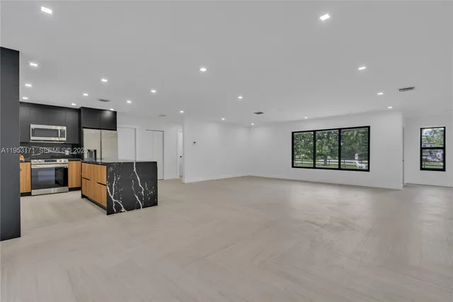 a view of kitchen with stainless steel appliances kitchen island granite countertop a large window in a house