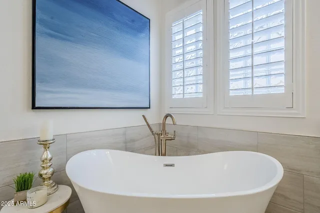 a white bath tub sitting in a bathroom next to a window
