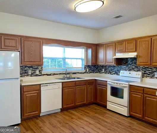 a kitchen with stainless steel appliances granite countertop a stove a sink cabinets and a refrigerator