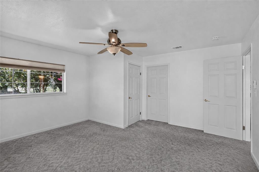 1612 Whitemound Road Sherman, TX 75090 - Photo 10 of 28 Spacious room featuring neutral carpeting, white walls, a large window with roller shades, a ceiling fan with light fixture, and multiple doors (Virtually Removed Items)
