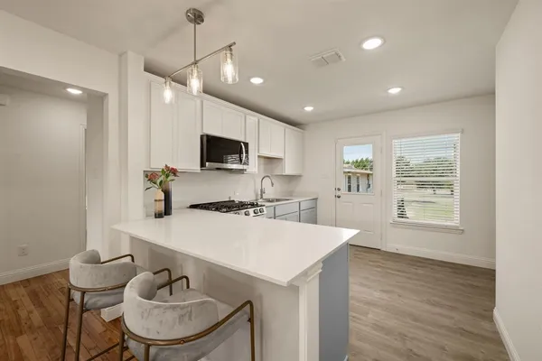a large white kitchen with stainless steel appliances granite countertop a stove and a sink
