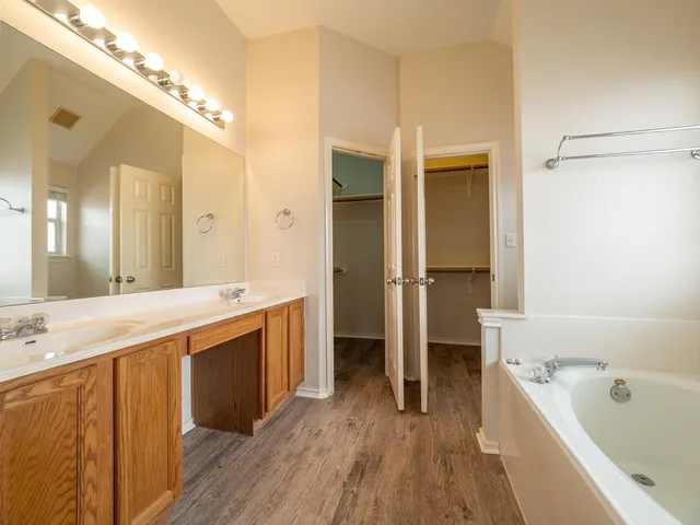 a spacious bathroom with a tub sink shower and a mirror