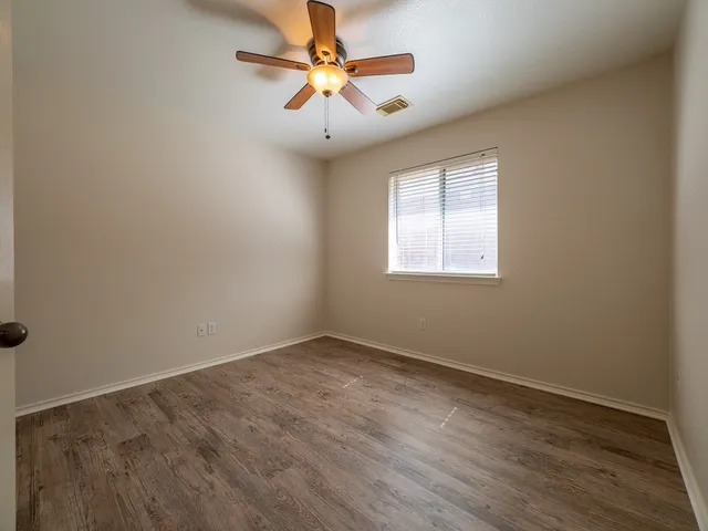an empty room with a window and a fan