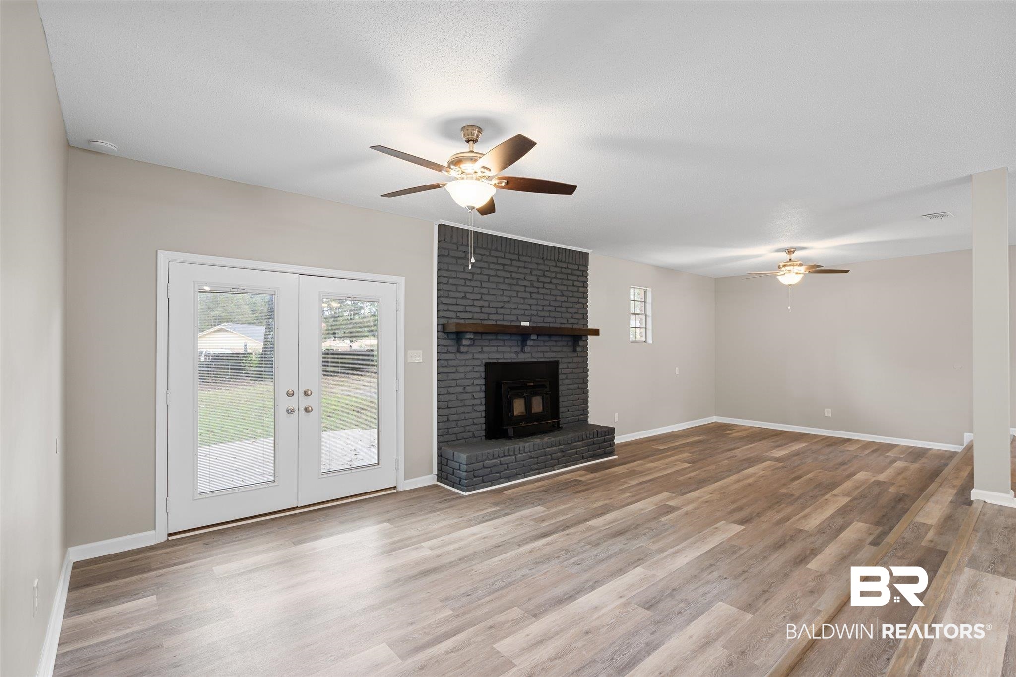 5015 Golfway Drive Eight Mile, AL 36613 - Photo 10 of 31 Unfurnished living room with french doors, light hardwood / wood-style flooring, ceiling fan, and a wood stove