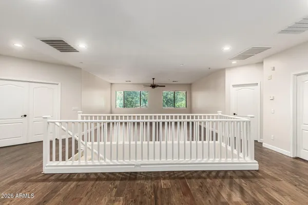 an empty room with wooden floor chandelier fan and windows