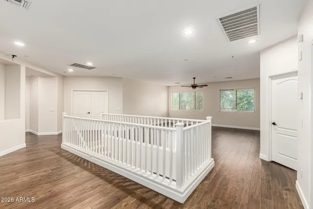 a view of empty room with wooden floor and ceiling fan