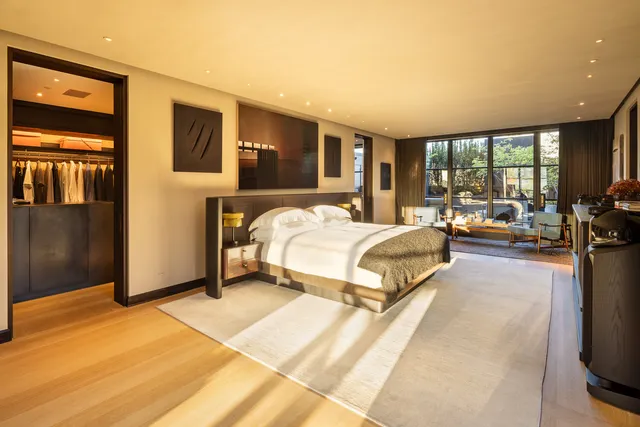 a bedroom with a large bed couch and a flat tv screen next to a window