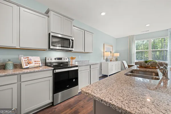 a living room with stainless steel appliances kitchen island granite countertop a couch a dining table and chairs with wooden floor