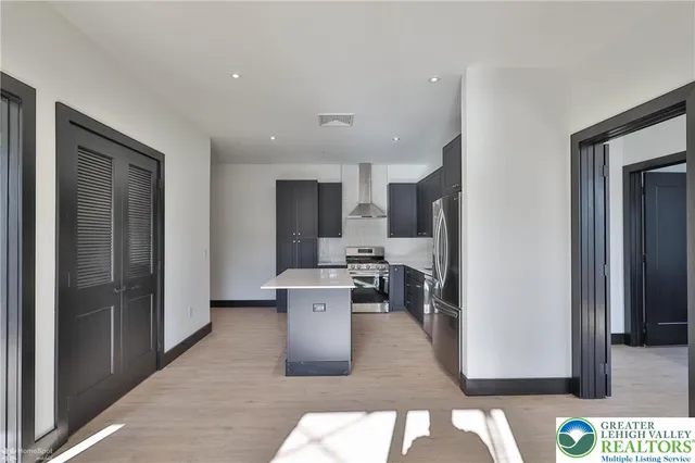 a living room with stainless steel appliances furniture a refrigerator and a kitchen sink