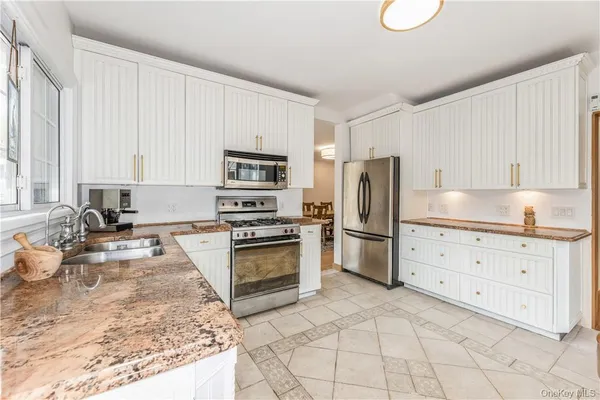 a kitchen with granite countertop a stove a sink and a refrigerator