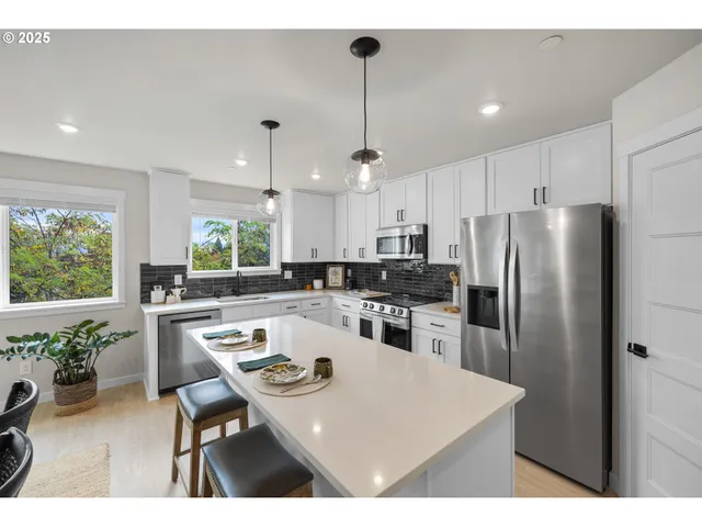 a kitchen with a refrigerator a stove a sink a dining table and chairs