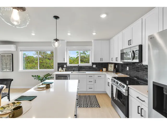 a kitchen with stainless steel appliances granite countertop a stove a sink dishwasher a refrigerator white cabinets and wooden floor