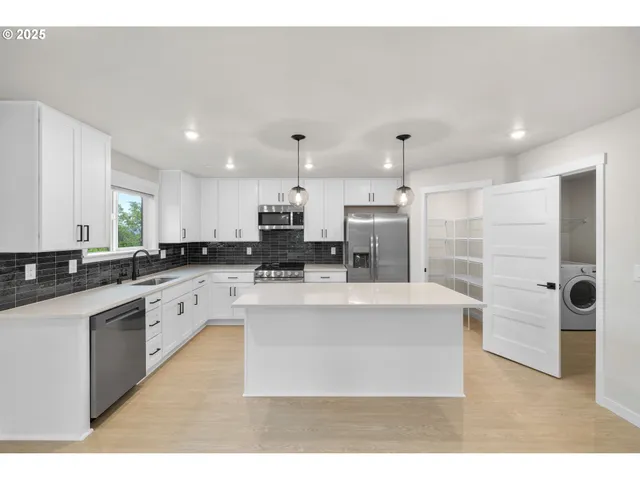 a kitchen with kitchen island a counter space a sink appliances and cabinets