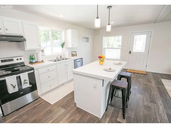 a kitchen with stainless steel appliances a dining table chairs refrigerator and sink
