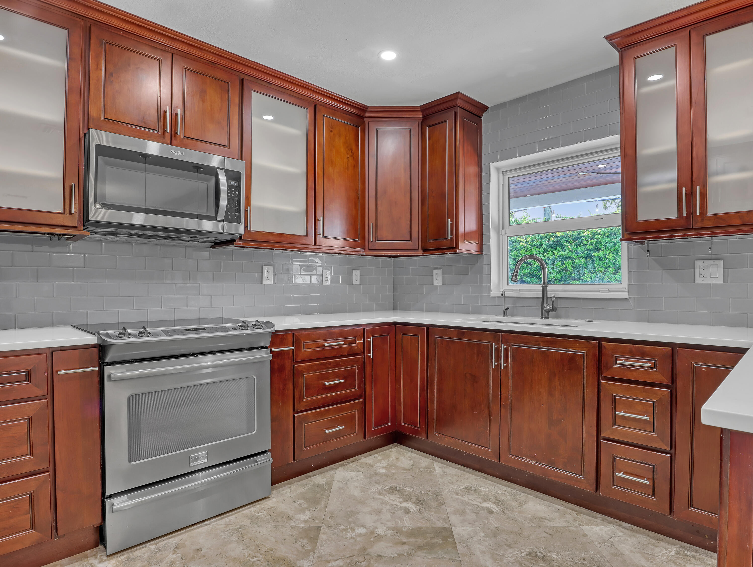 1298 Northwest 4th Street Boca Raton, FL 33486 - Photo 11 of 36 a kitchen with stainless steel appliances granite countertop wooden cabinets a stove a sink and a microwave