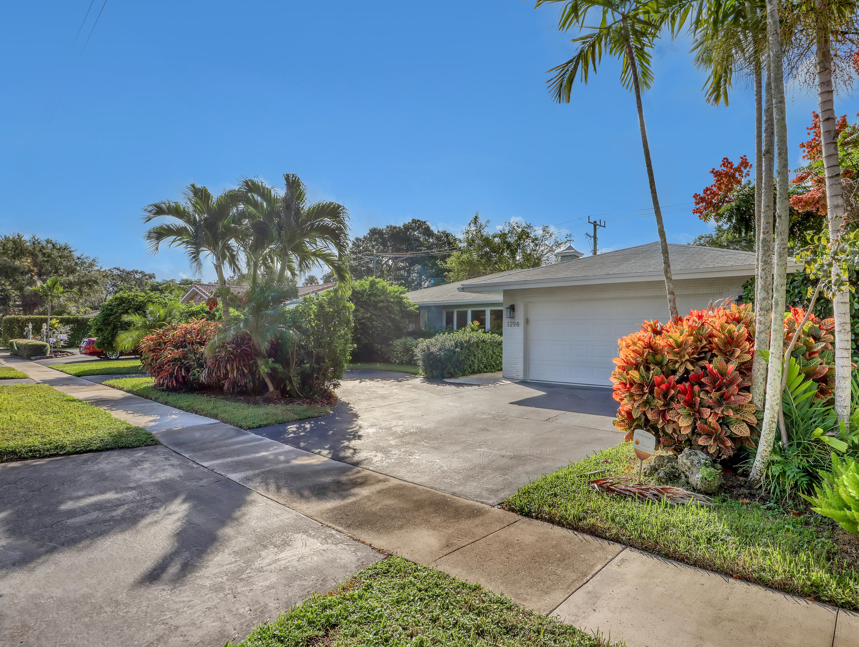 1298 Northwest 4th Street Boca Raton, FL 33486 - Photo 2 of 36 a front view of a house with a garden and a yard