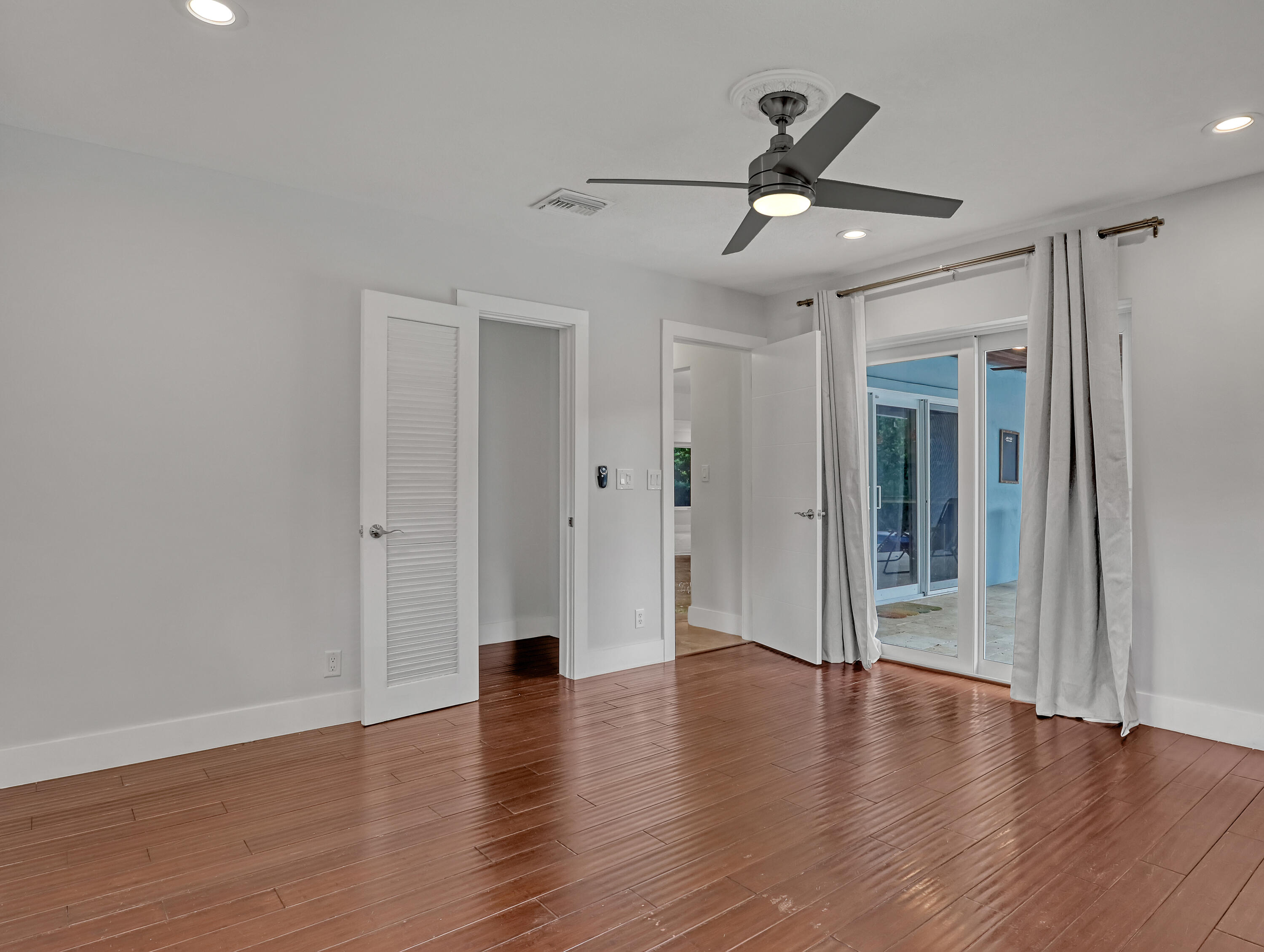 1298 Northwest 4th Street Boca Raton, FL 33486 - Photo 21 of 36 a view of an empty room with wooden floor and a ceiling fan