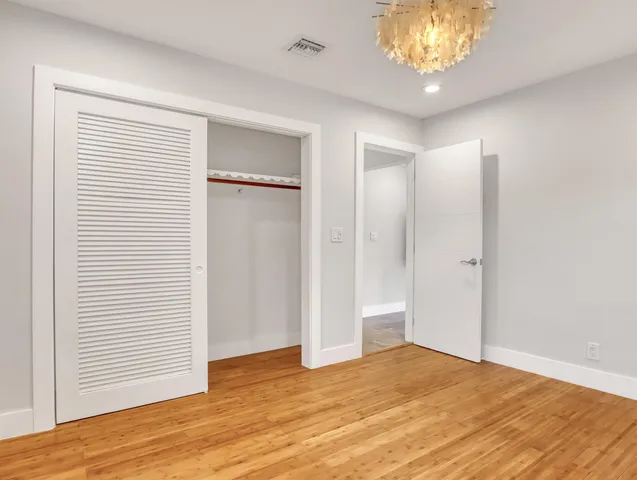 a view of an empty room with wooden floor and a chandelier