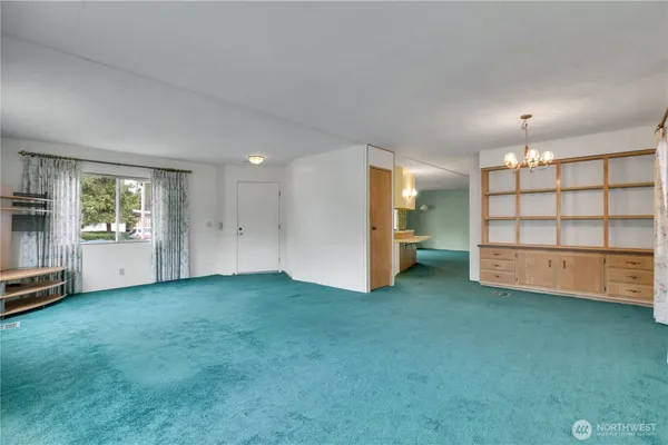 a view of an empty room with a window and kitchen