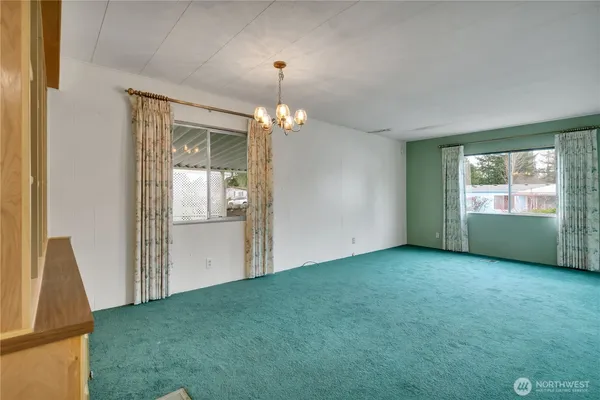 an empty room with chandelier fan and windows