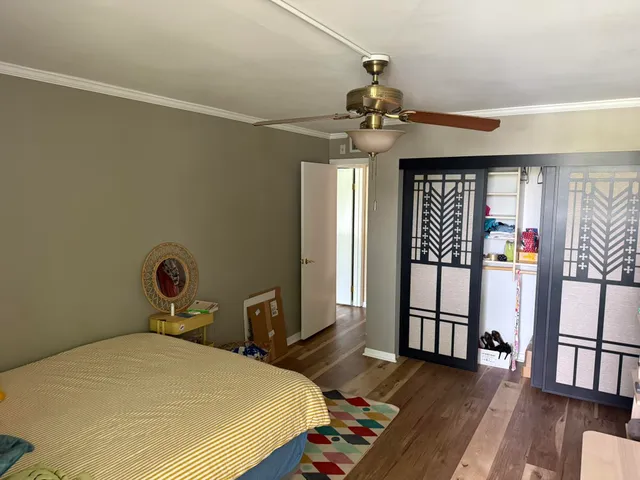 a bedroom with a bed a dresser and wooden floor