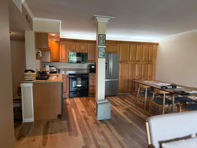 a kitchen with stainless steel appliances granite countertop a stove a sink dishwasher a refrigerator white cabinets and wooden floor