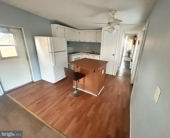 a view of a refrigerator in kitchen and an empty room