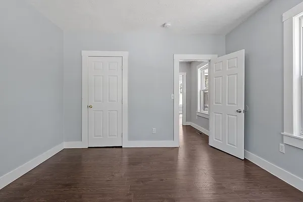 an empty room with wooden floor & windows and bathroom