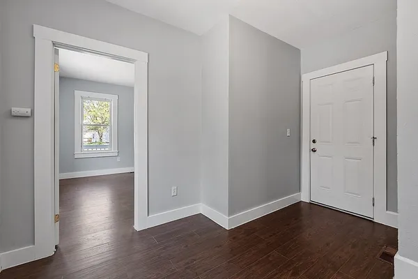 a view of an empty room with wooden floor and a window