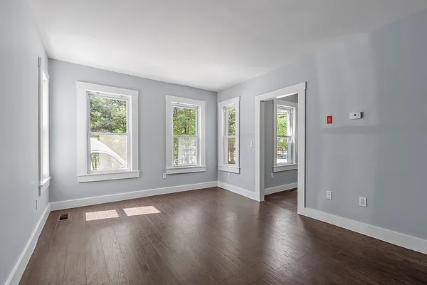 an empty room with wooden floor and windows
