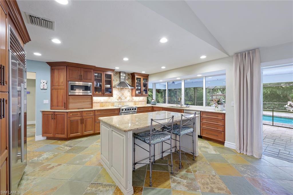 2113 Imperial Golf Course Boulevard Naples, FL 34110 - Photo 17 of 42 a kitchen with stainless steel appliances kitchen island granite countertop a refrigerator and cabinets
