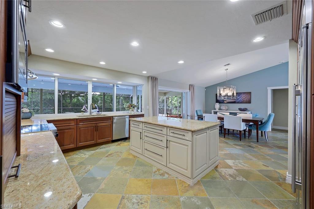 2113 Imperial Golf Course Boulevard Naples, FL 34110 - Photo 18 of 42 a kitchen with stainless steel appliances granite countertop a refrigerator a sink a dining table and chairs