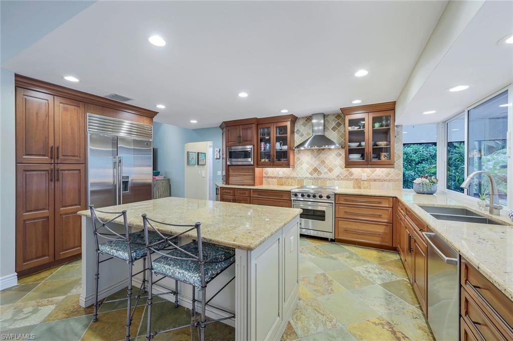 2113 Imperial Golf Course Boulevard Naples, FL 34110 - Photo 19 of 42 a kitchen with stainless steel appliances kitchen island granite countertop a sink and cabinets
