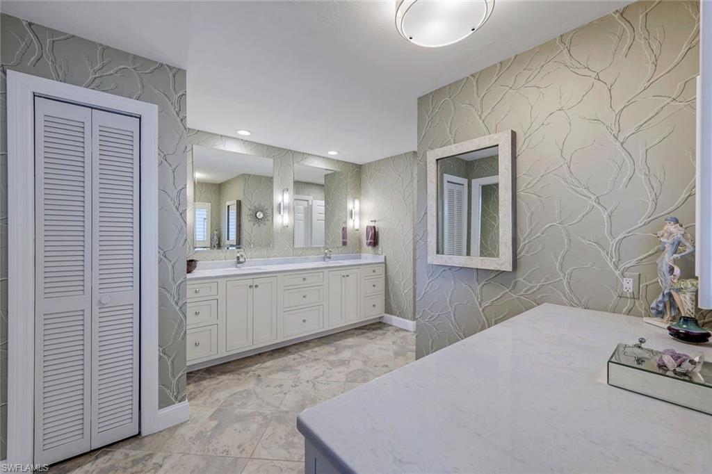 2113 Imperial Golf Course Boulevard Naples, FL 34110 - Photo 24 of 42 a room with a bed a dresser and mirror