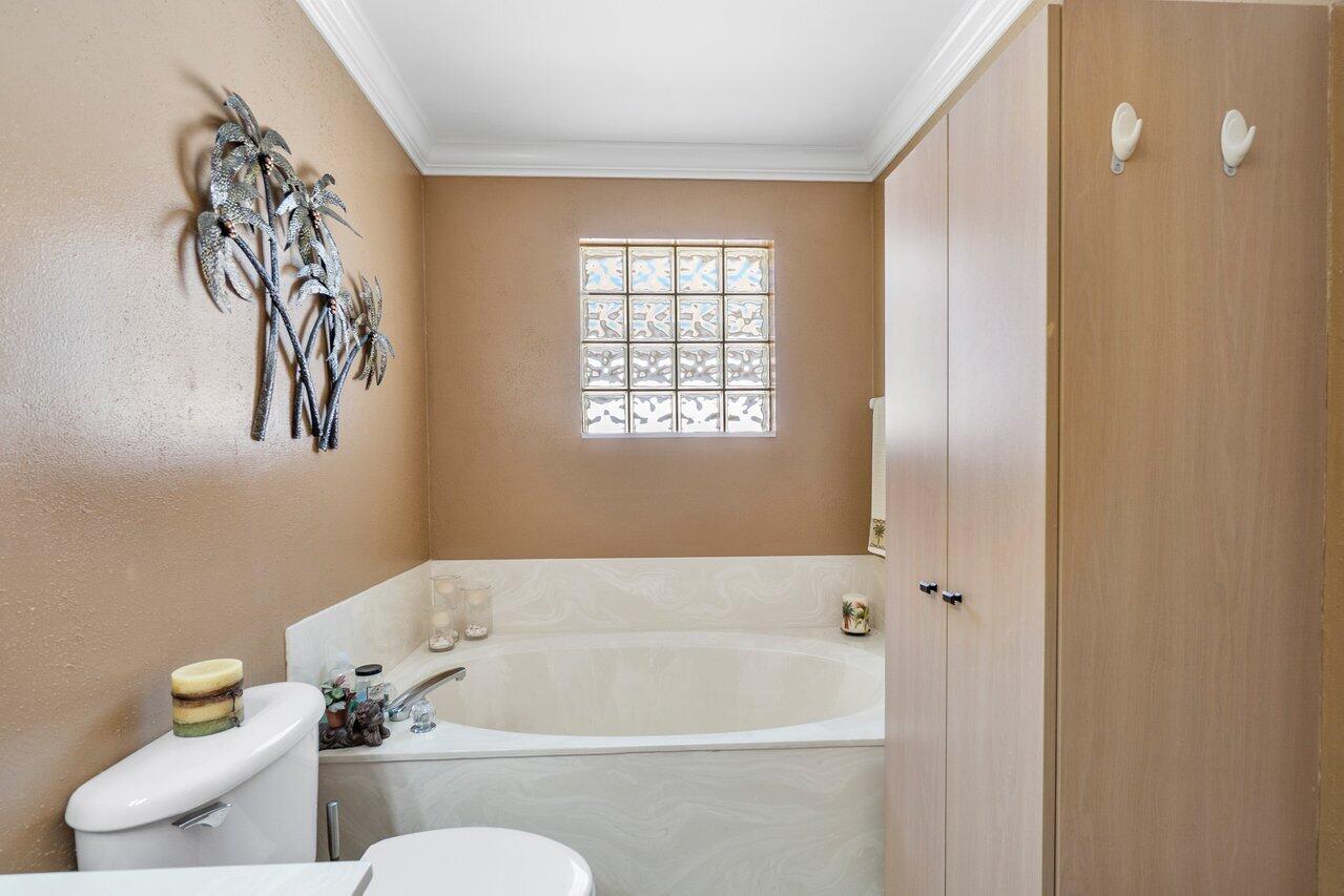 1410 Bethpage Way Greenacres, FL 33413 - Photo 14 of 29 a bath tub sitting next to a white toilet and a shower curtain