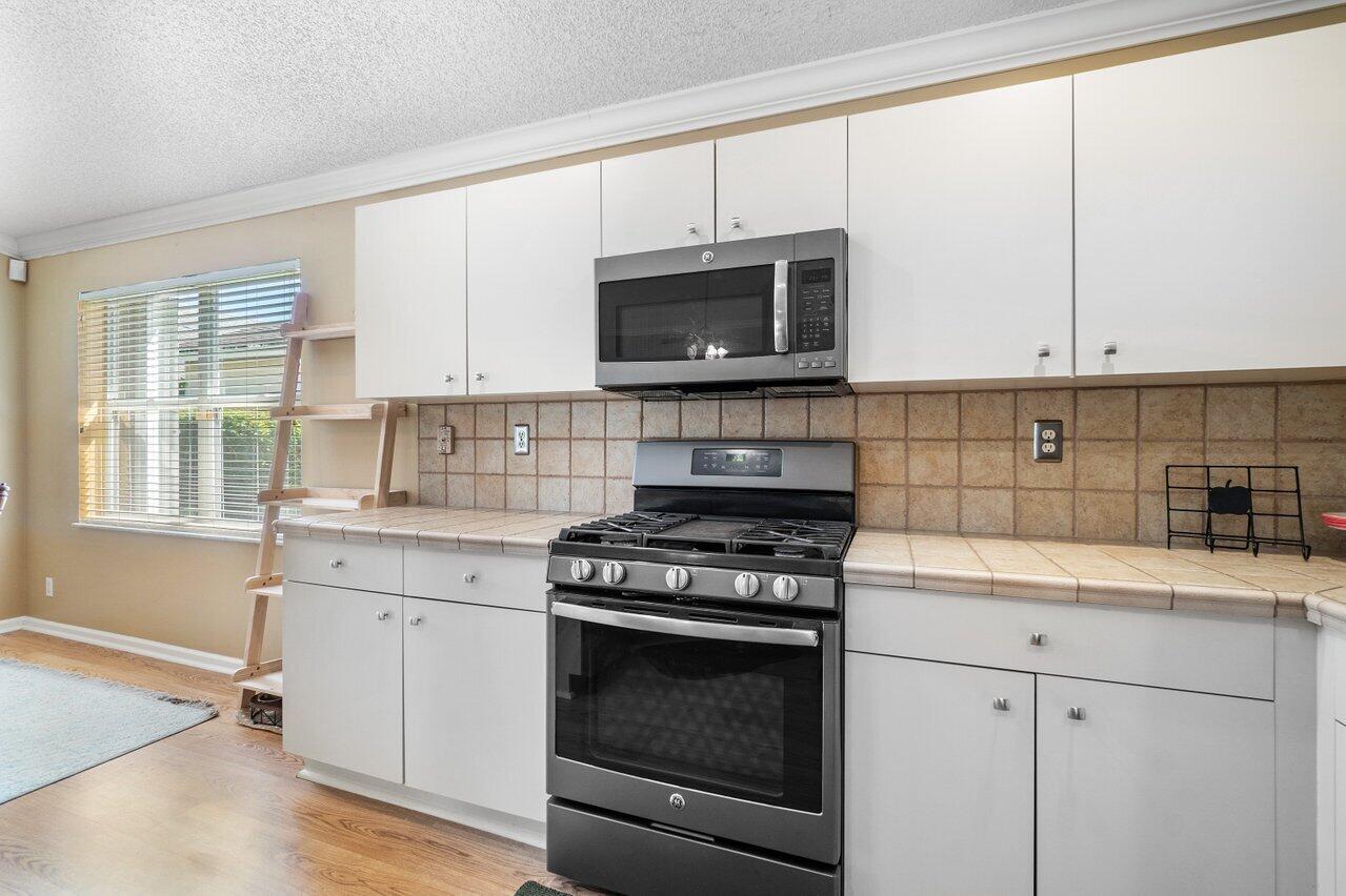 1410 Bethpage Way Greenacres, FL 33413 - Photo 7 of 29 a kitchen with granite countertop white cabinets and a stove top oven