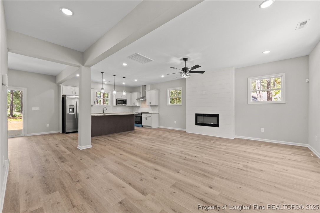 15980 Old Orchard Court Wagram, NC 28396 - Photo 16 of 33 an empty room with wooden floor and a kitchen