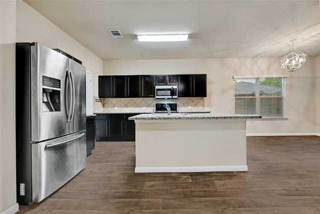 an empty room with a chandelier fan and windows