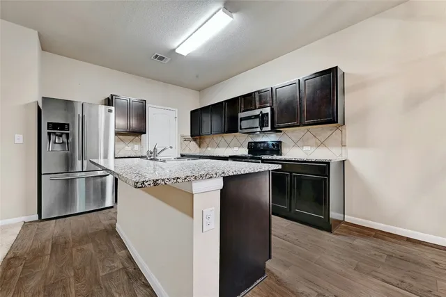 a kitchen with kitchen island stainless steel appliances a stove refrigerator sink and microwave