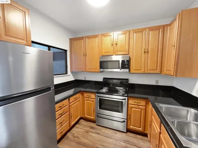 a kitchen with granite countertop a refrigerator a stove a sink and dishwasher