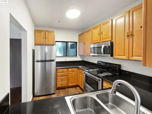 a kitchen with stainless steel appliances granite countertop a refrigerator a sink and a stove