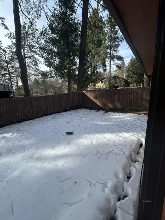 a view of backyard with wooden fence and trees