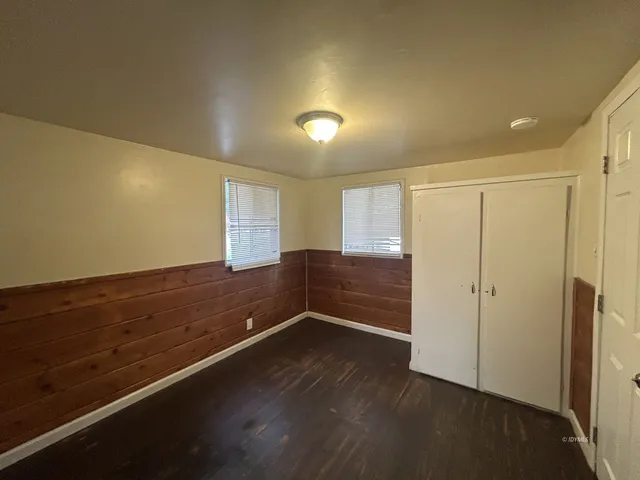an empty room with wooden floor cabinet and windows