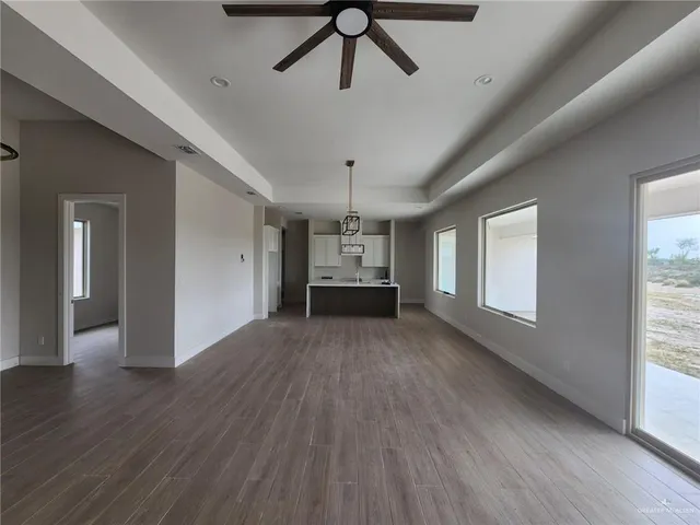 a view of an empty room with wooden floor and windows