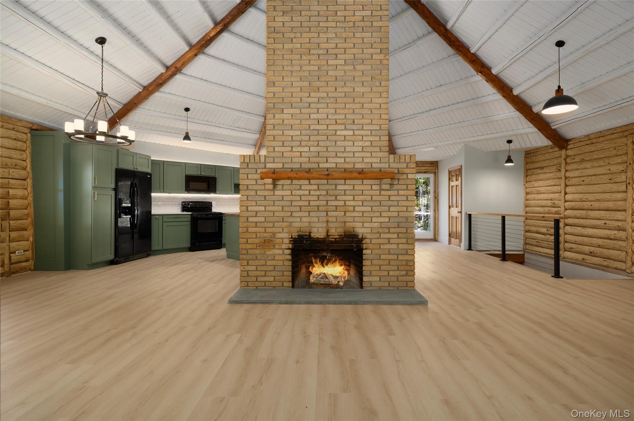 568 Oak Summit Road Millbrook, NY 12545 - Photo 14 of 50 Unfurnished living room with rustic walls, high vaulted ceiling, light wood-type flooring, a fireplace, and a chandelier