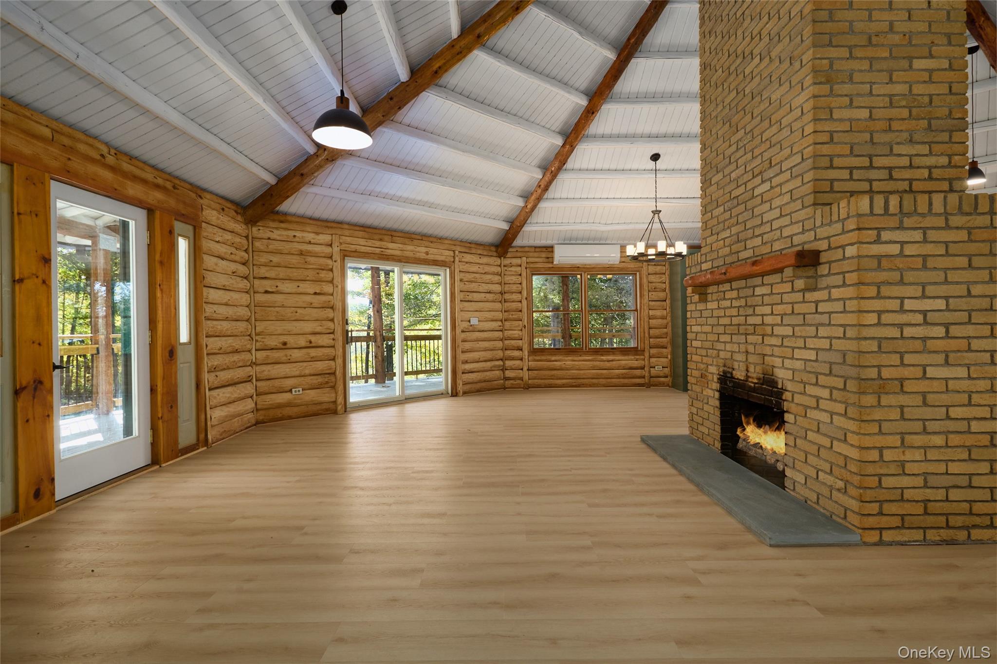 568 Oak Summit Road Millbrook, NY 12545 - Photo 16 of 50 Unfurnished living room featuring beamed ceiling, high vaulted ceiling, a fireplace, wood finished floors, and a chandelier