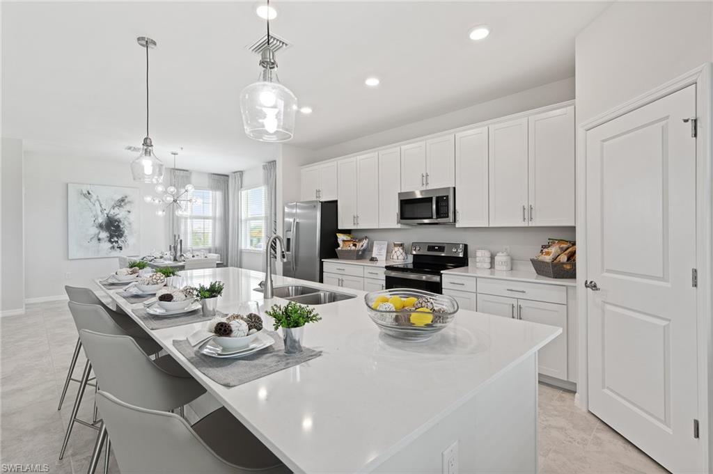 6008 Ellerston Way Avenue, Unit 1021 Immokalee, FL 34142 - Photo 17 of 50 Kitchen with white cabinetry, decorative light fixtures, a kitchen bar, a center island with sink, and recessed lighting