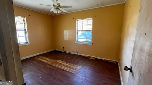 a view of an empty room with wooden floor and a window